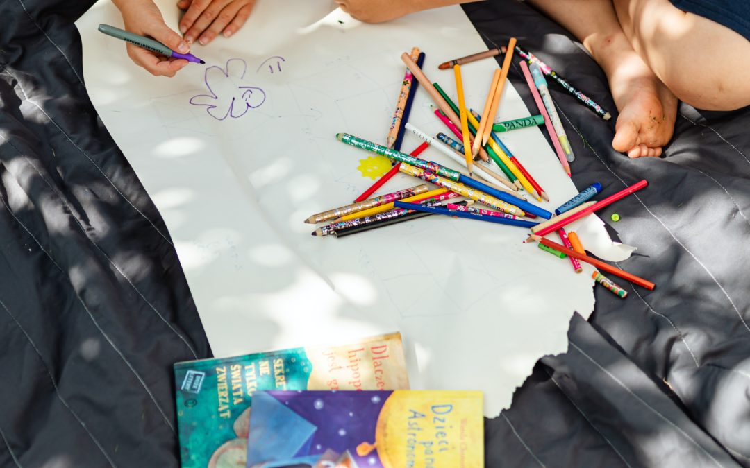 child and grown up sitting next to a large piece of paper, writing and drawing.