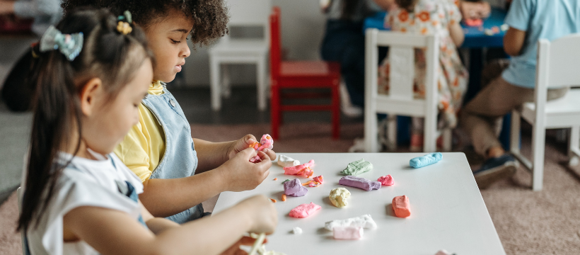 Two young children at a table playing with coloured play dough